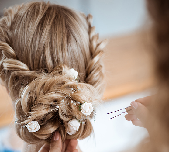 female hairdresser making hairstyle to blonde girl in beauty salon.